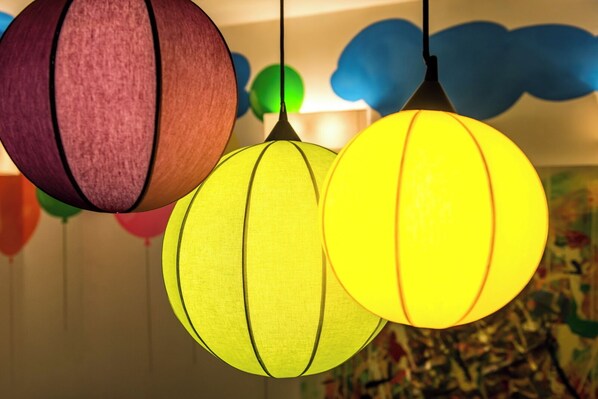 A room with a colorful abstract painting on the wall and a ceiling with hanging spherical light fixtures.