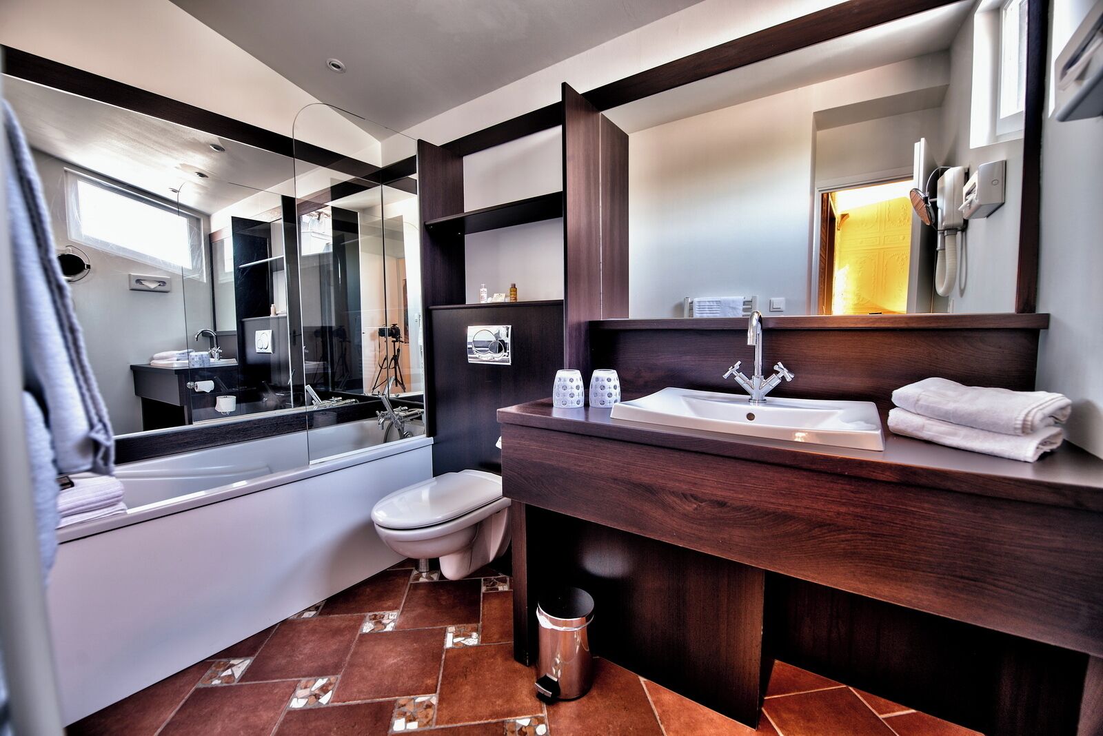 A modern bathroom with a large mirror, a sink, and a toilet.