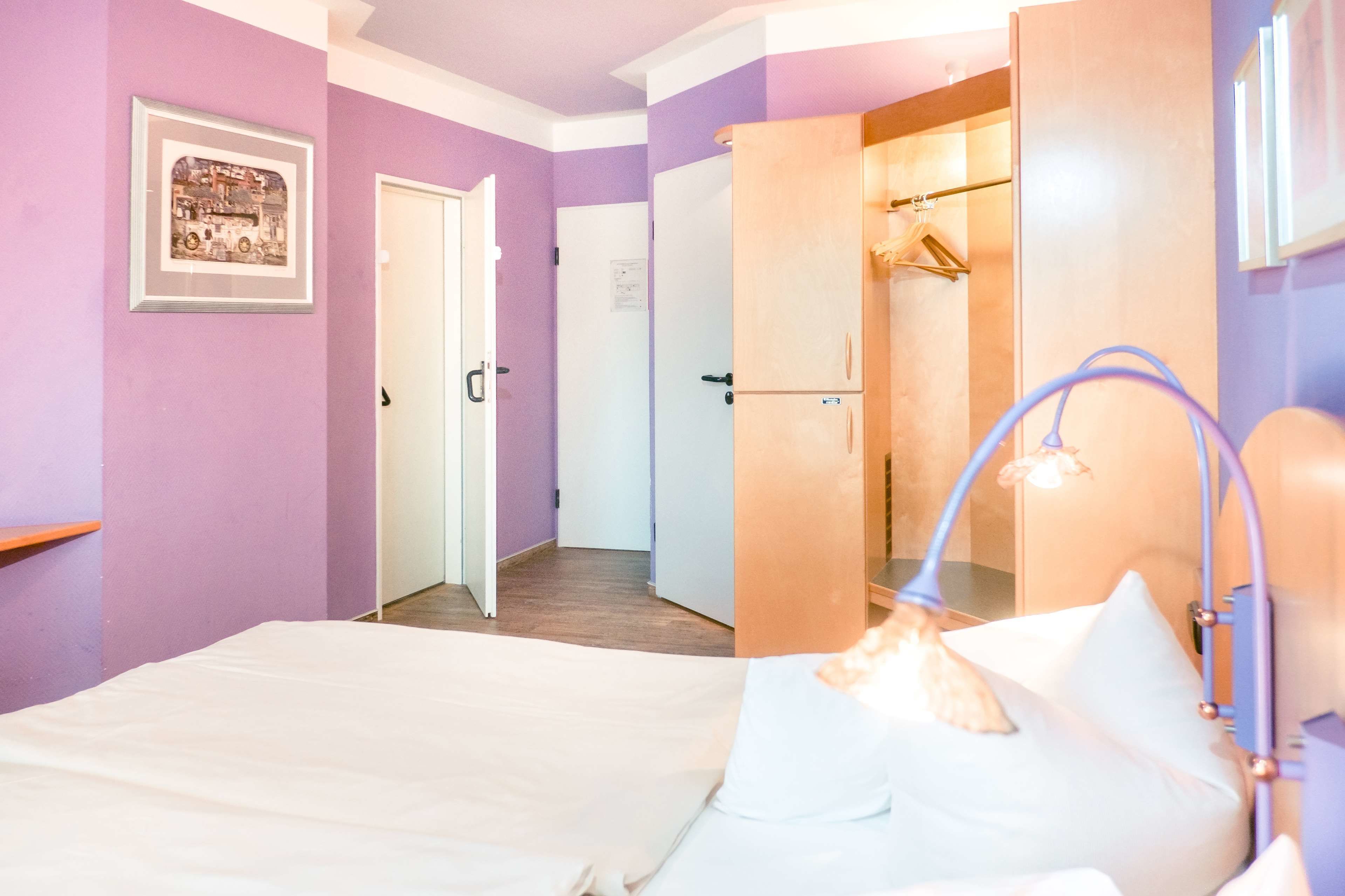 A bedroom with a bed, a wardrobe, and a bathroom with a shower.