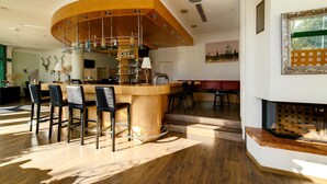 Eine moderne Bar mit einer gebogenen Holztresen, Barhocker und einer Glastrennwand.