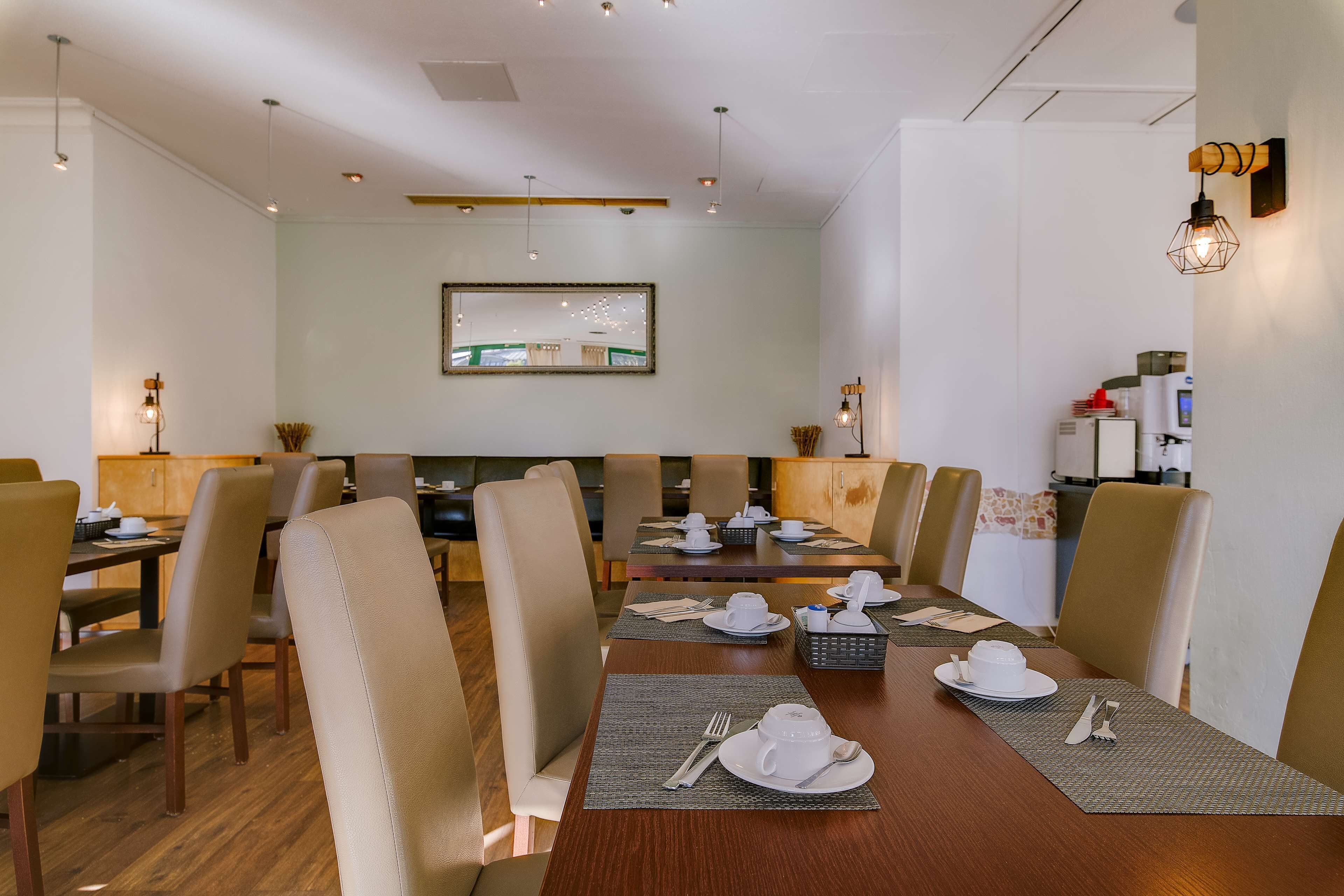 A dining area with a long wooden table set for a meal, surrounded by beige chairs.