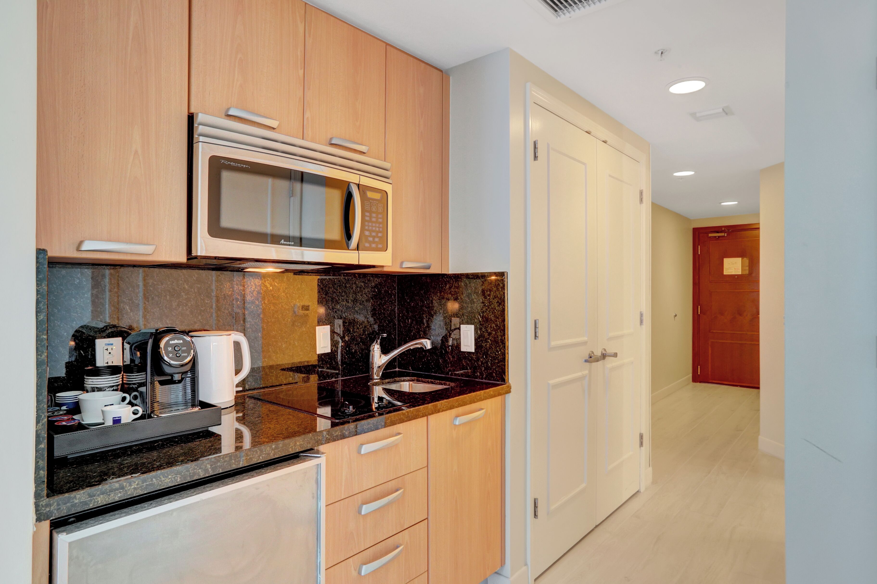 Cocina moderna con microondas integrado, cafetera y lavamanos.
