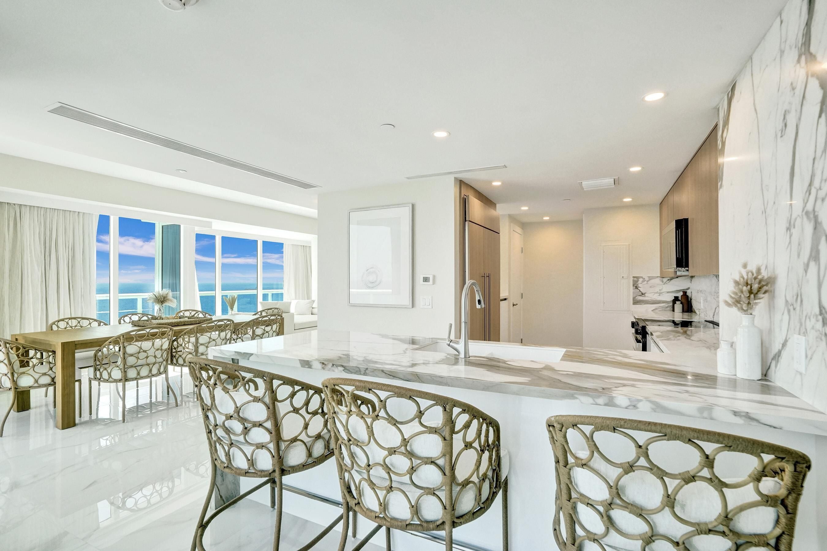 A modern kitchen with a marble countertop, stainless steel appliances, and a view of the ocean.