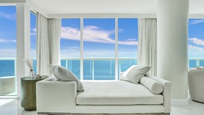 A modern living room with a large window overlooking a body of water, a white sofa, and a round side table.