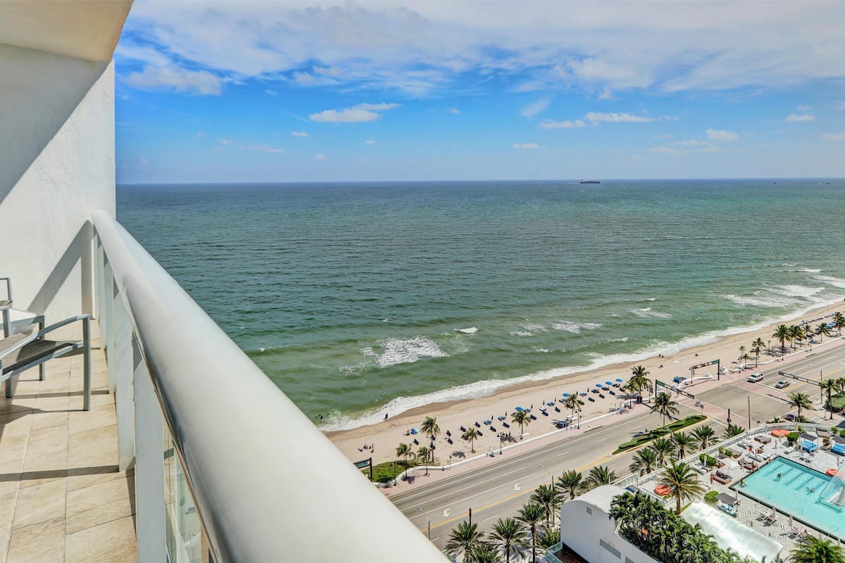 A balcony with a view of the ocean and a beach.