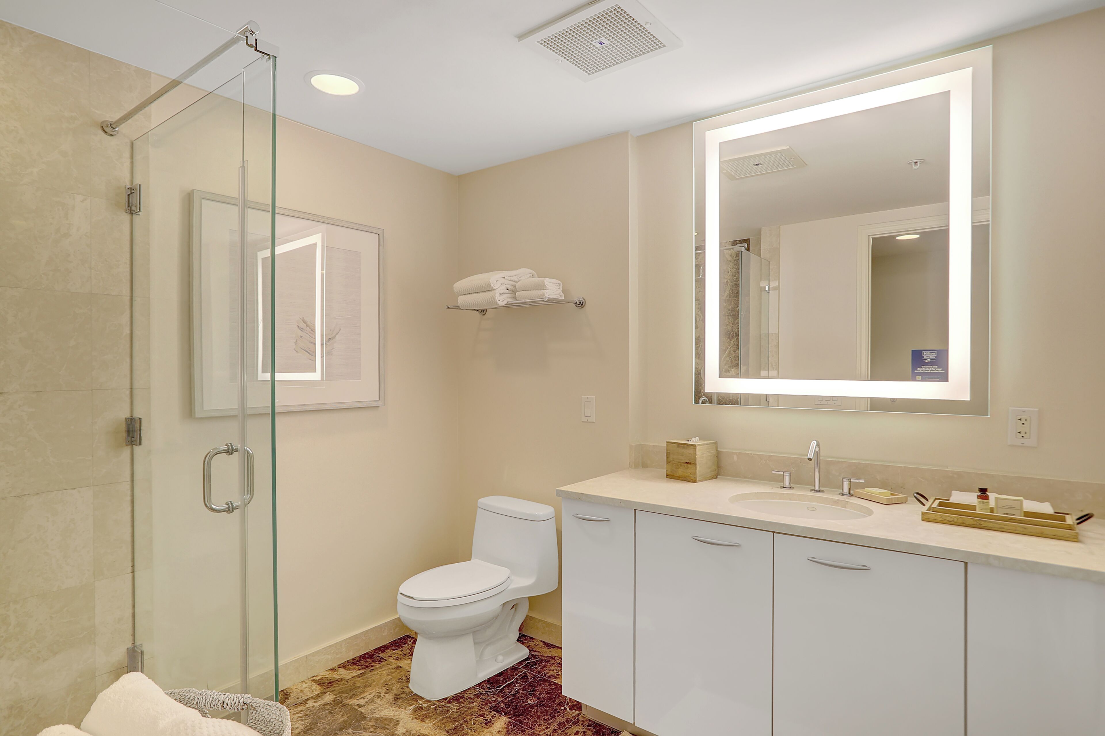 Une salle de bain avec une douche à parois de verre, des toilettes, un lavabo et un grand miroir.