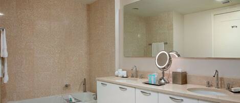 A modern bathroom with a bathtub, two sinks, and a large mirror.