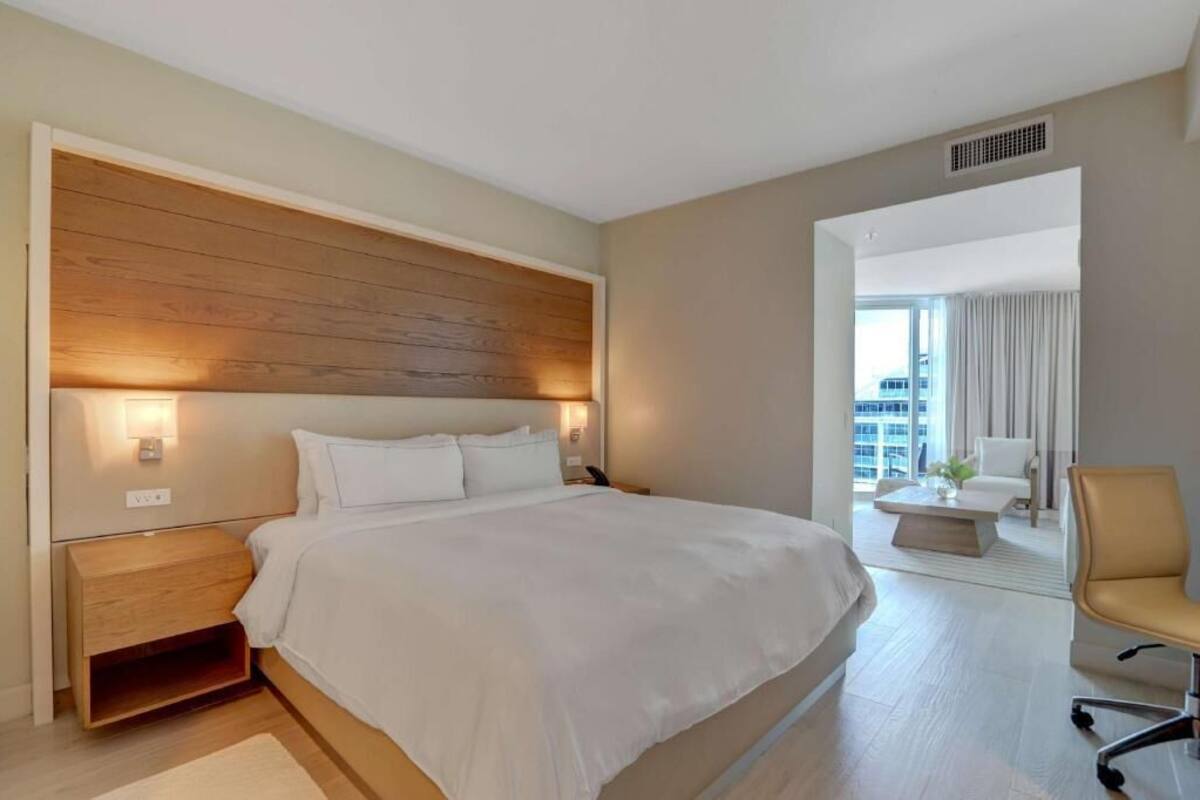 A modern hotel room with a large bed, bedside tables, a desk, and a chair.