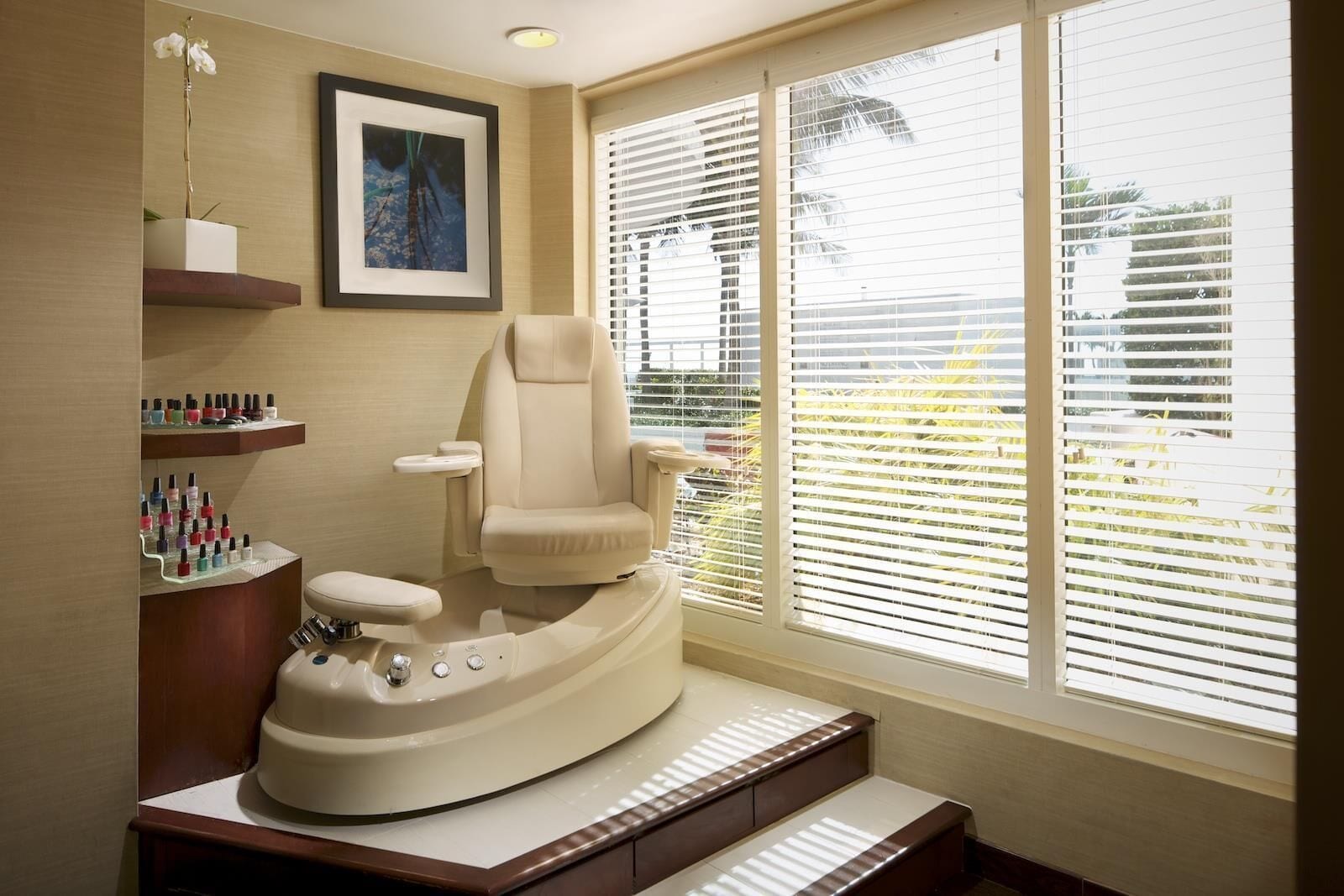 Une salle de bain moderne avec un meuble-lavabo aux lignes courbes, une chaise et une grande fenêtre équipée de stores.