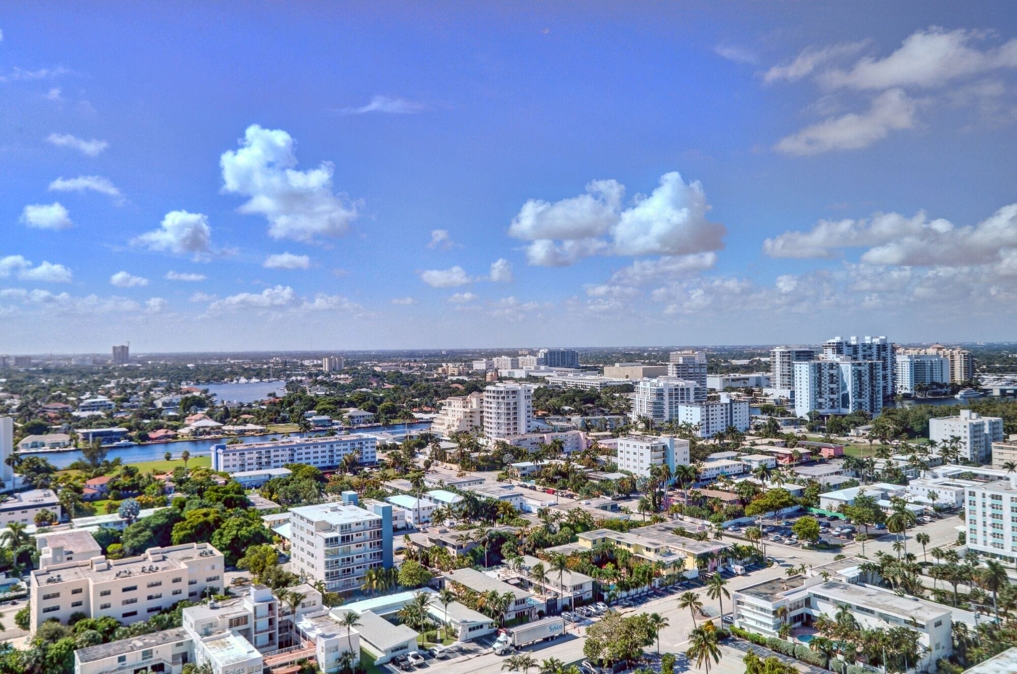 Une vue urbaine avec de hauts immeubles, un port de plaisance et un ciel dégagé.