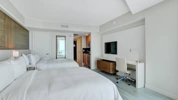 Una habitación de hotel moderna con dos camas, un escritorio, un televisor y una kitchenette.