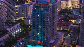 A high-rise hotel with multiple floors, a pool area, and a beachside location.