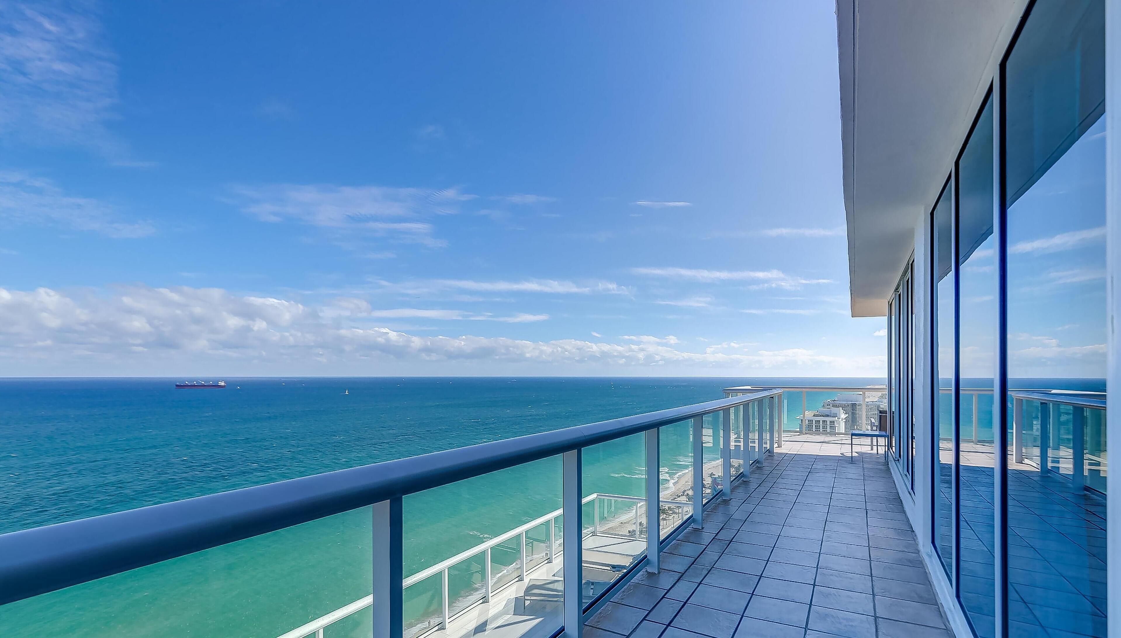 A balcony with a clear view of the ocean and distant ships.
