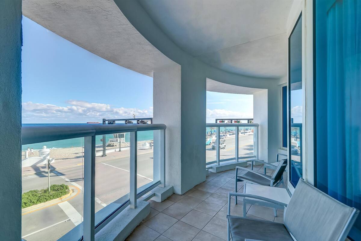 A balcony with a view of a beach and road.