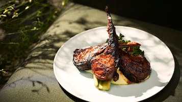 Un plato con carne a la parrilla y verduras sobre una fuente blanca.