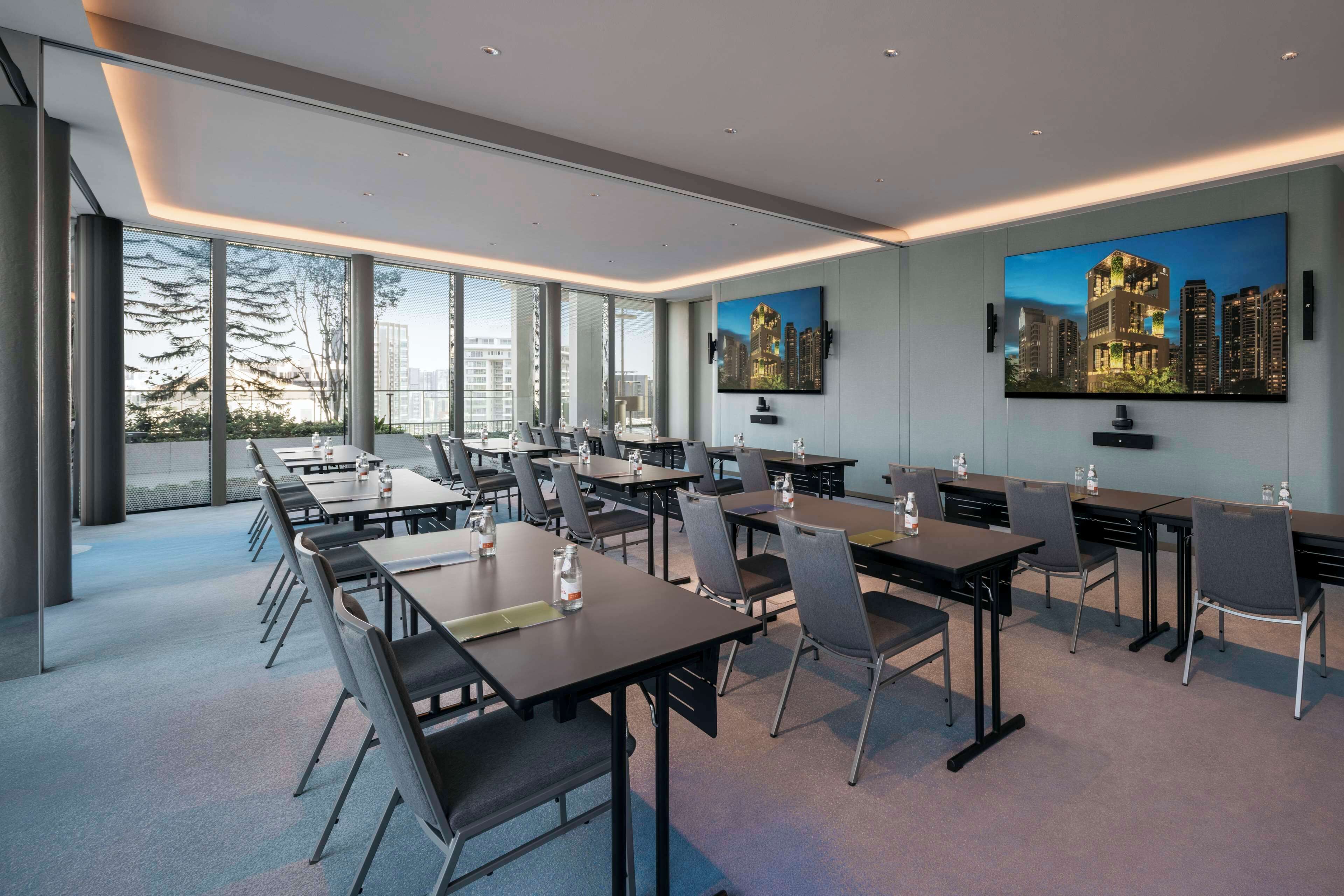 Una sala de conferencias moderna con mesas grandes, sillas y cuadros de paisajes urbanos en las paredes.