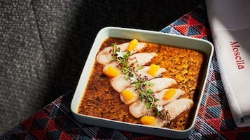 A dish of fish in a white bowl on a checkered cloth.