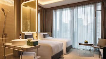 Habitación de hotel con una cama grande, un baño independiente con ducha, un tocador con lavabo y una mesita con un frutero.