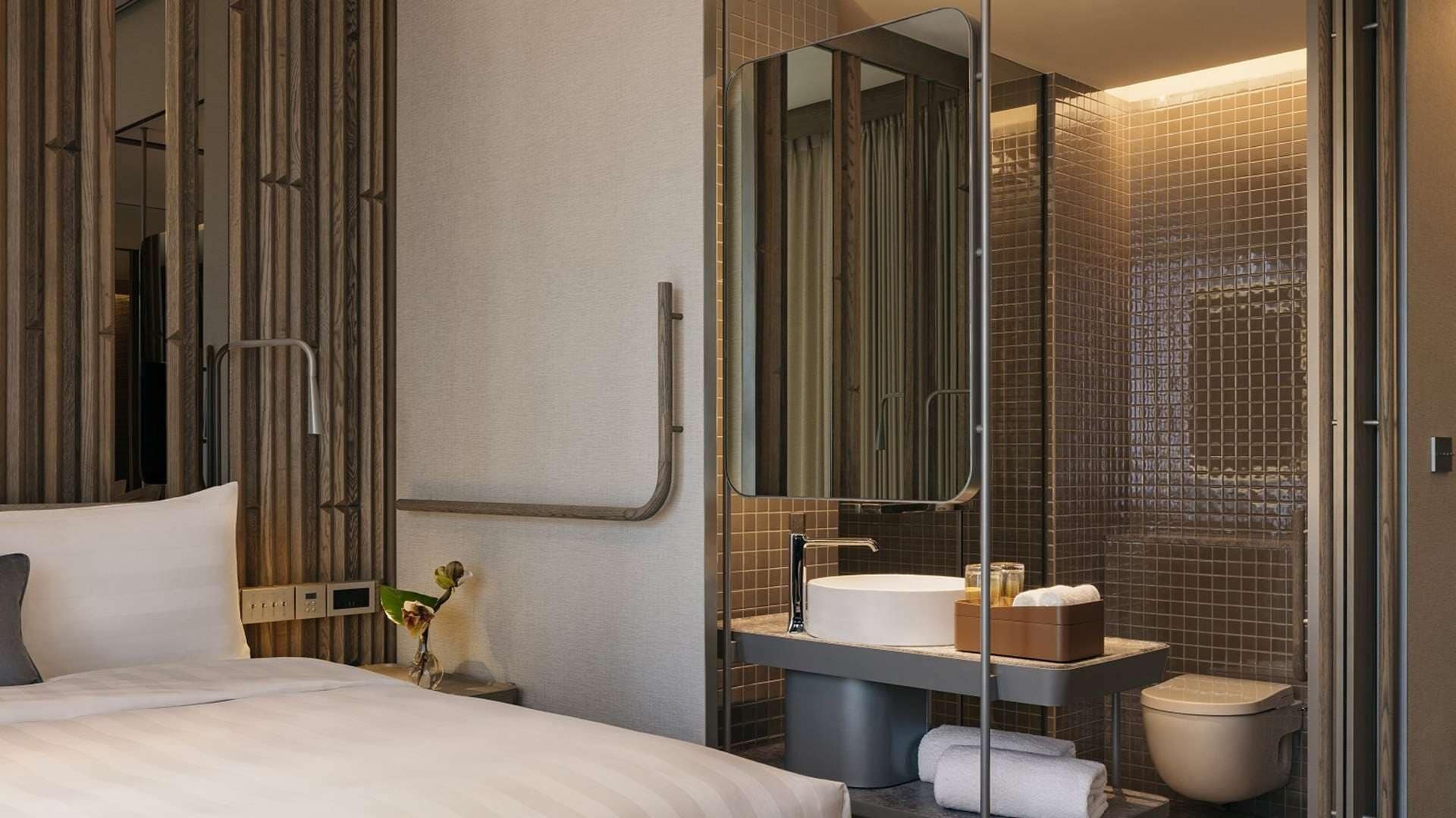 Ein Hotelzimmer mit einem Bett, einem Nachttisch mit Lampe, einem Spiegel, einem Waschbecken und einer Toilette.