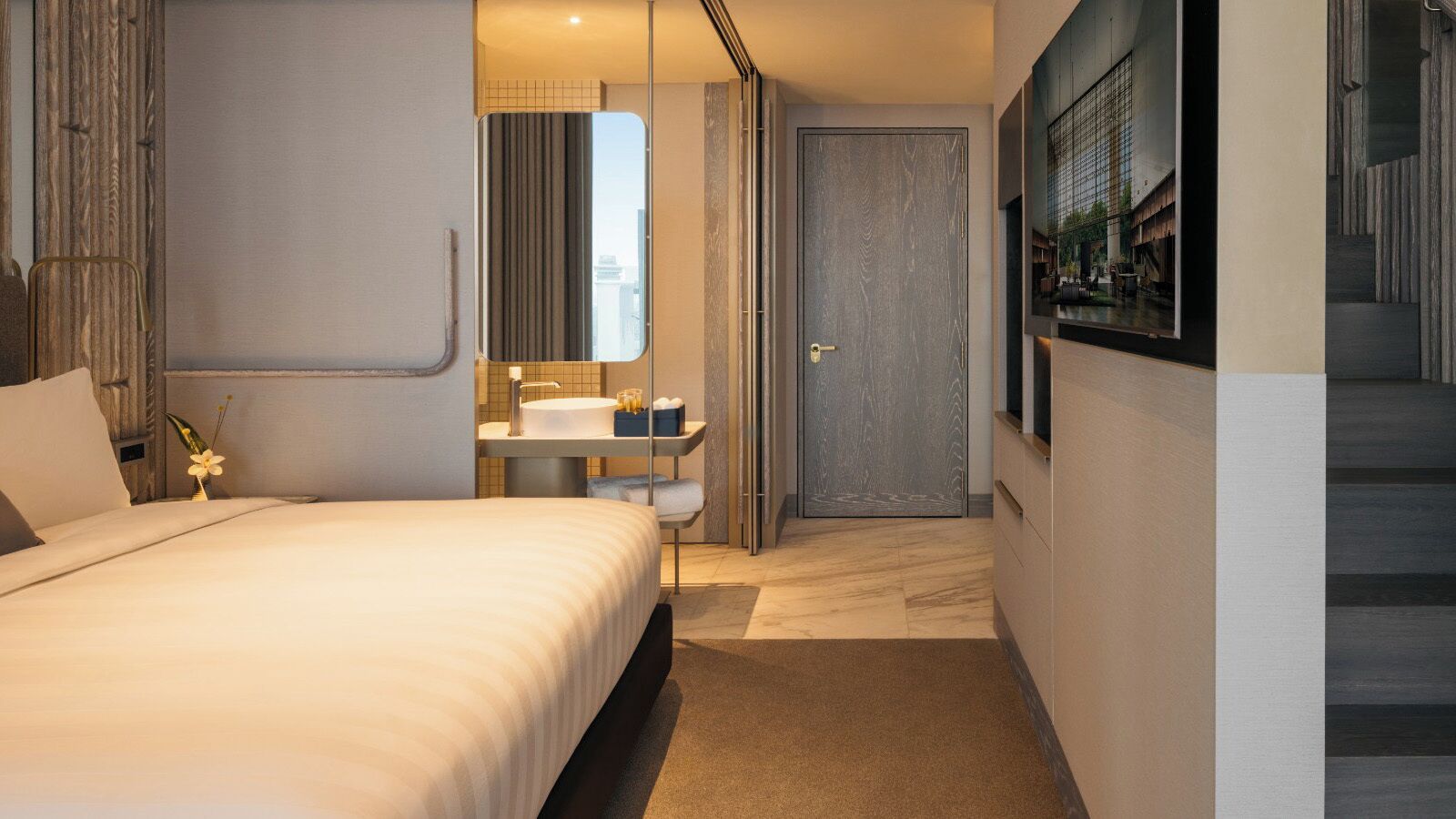A modern hotel room with a large bed, a bathroom with a mirror, and a view of the city through a window.
