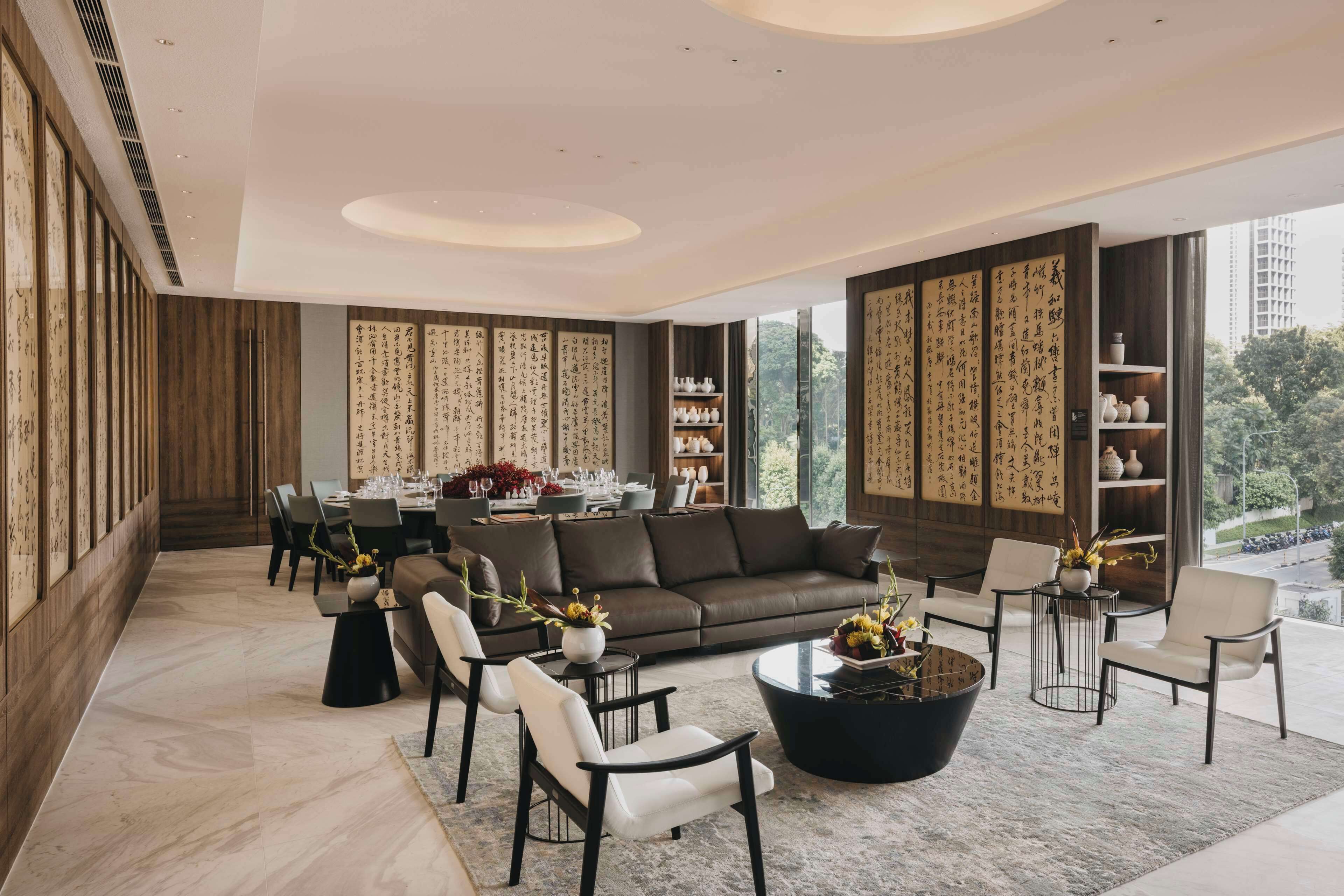A modern living room with a brown leather sofa, black and white chairs, a coffee table, and a dining area with a table set for four.