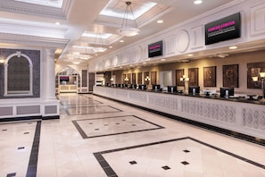 Un hall d’hôtel doté d’un long comptoir d’accueil, de plusieurs espaces salon et d’un plafond agrémenté de verrières.