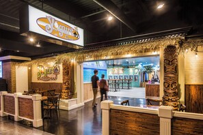 Een restaurantruimte met een strandthema, inclusief een bord met de tekst 'Yogurt Beach' en tropische decoratie.