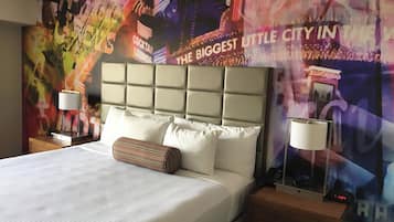 A hotel room with a large bed, two bedside tables, a headboard, and a vibrant mural on the wall.