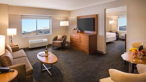 A hotel room with a large window, a flat-screen TV, a sofa, a dining table, and a minibar. - Circus Circus Reno Hotel & Casino - A Caesars Rewards Destination (Reno)