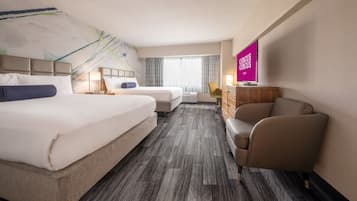 Una habitación de hotel con dos camas, un escritorio, una silla y un televisor.