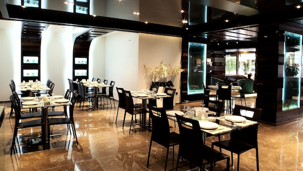 A modern restaurant with multiple dining tables and chairs, a polished marble floor, and a large window offering a view of the outdoors. - Imperial Suites Hotel (Beirut)