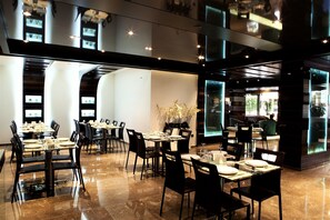 A modern restaurant with multiple dining tables and chairs, a polished marble floor, and a large window offering a view of the outdoors. - Imperial Suites Hotel (Beirut)