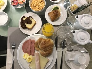 Desayuno con platos de comida, un tetera y un vaso de jugo.