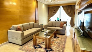 A modern living room with two sofas, a glass coffee table, a TV, and a chandelier. - Imperial Suites Hotel (Beirut)