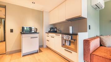 A compact kitchen with white cabinets, a black countertop, and a stainless steel oven.