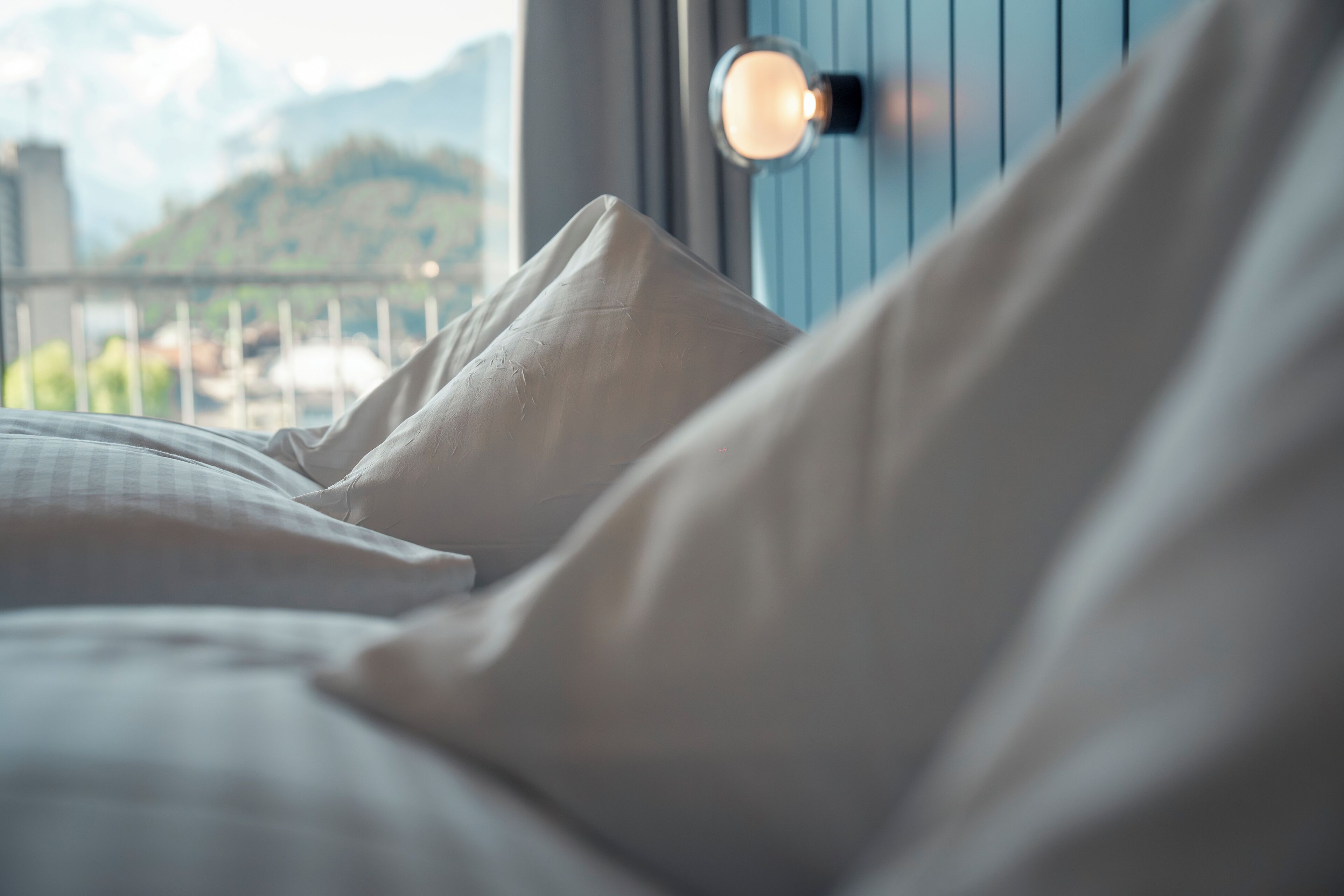 Ein Bett mit weißen Leinen und einer wandmontierten Lampe.