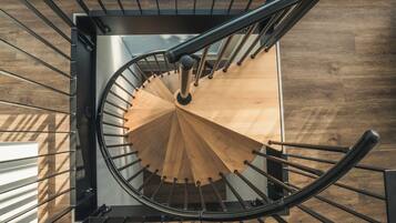 Una escalera de caracol con barandilla de madera y balaustradas de metal, que conduce a un piso superior.
