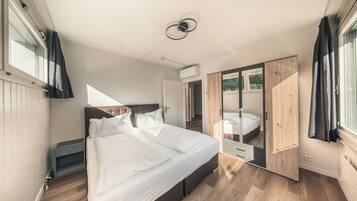 A bedroom with a bed, a wardrobe, a nightstand, and a window.
