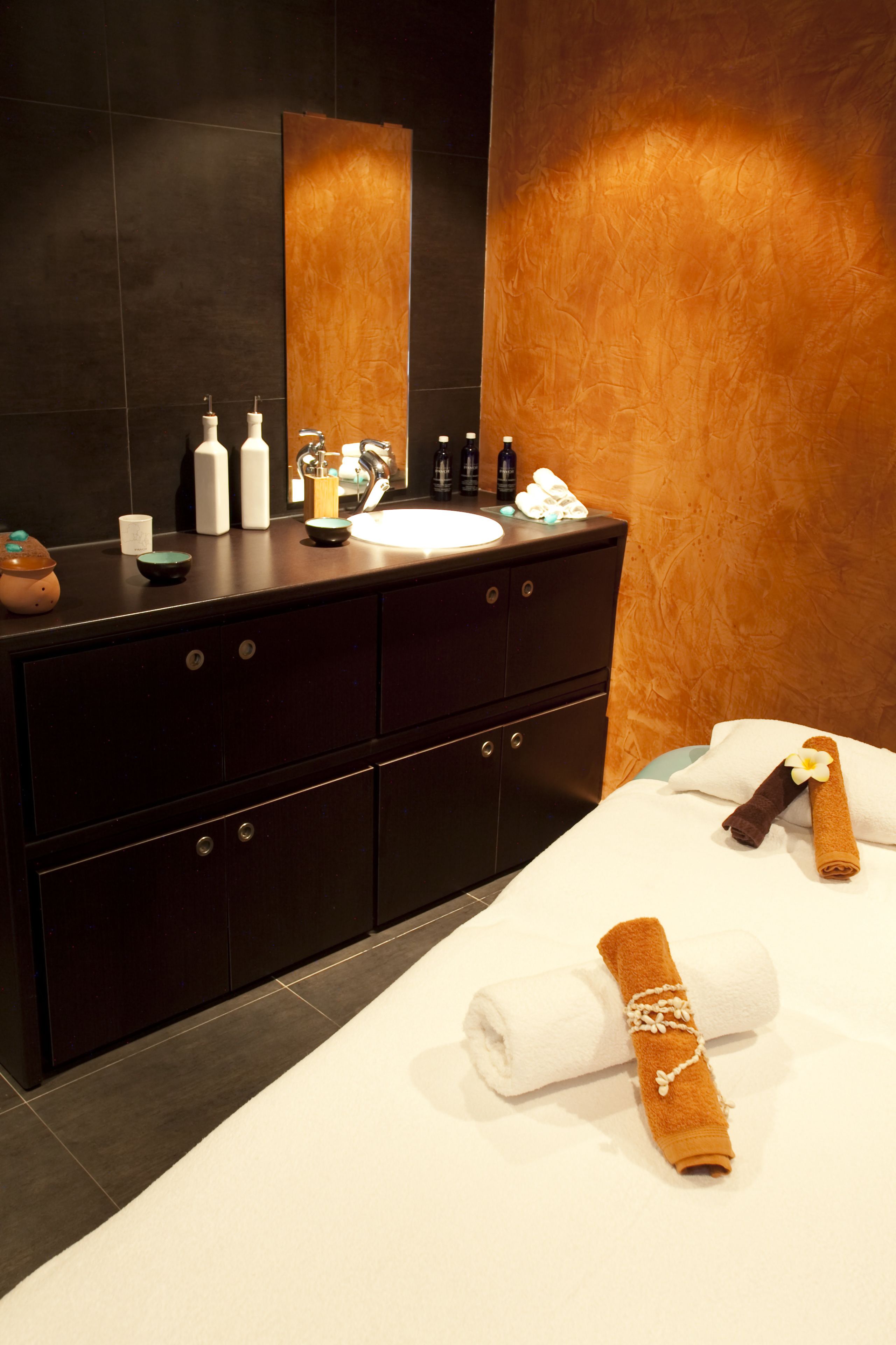 Un baño moderno con tocador de madera oscura, un espejo grande y un lavabo blanco. Hay toallas y artículos de tocador sobre el tocador.