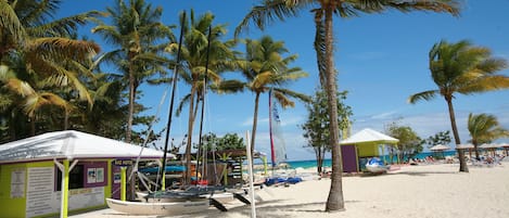 Une plage bordée de palmiers, un petit kiosque et un bateau.