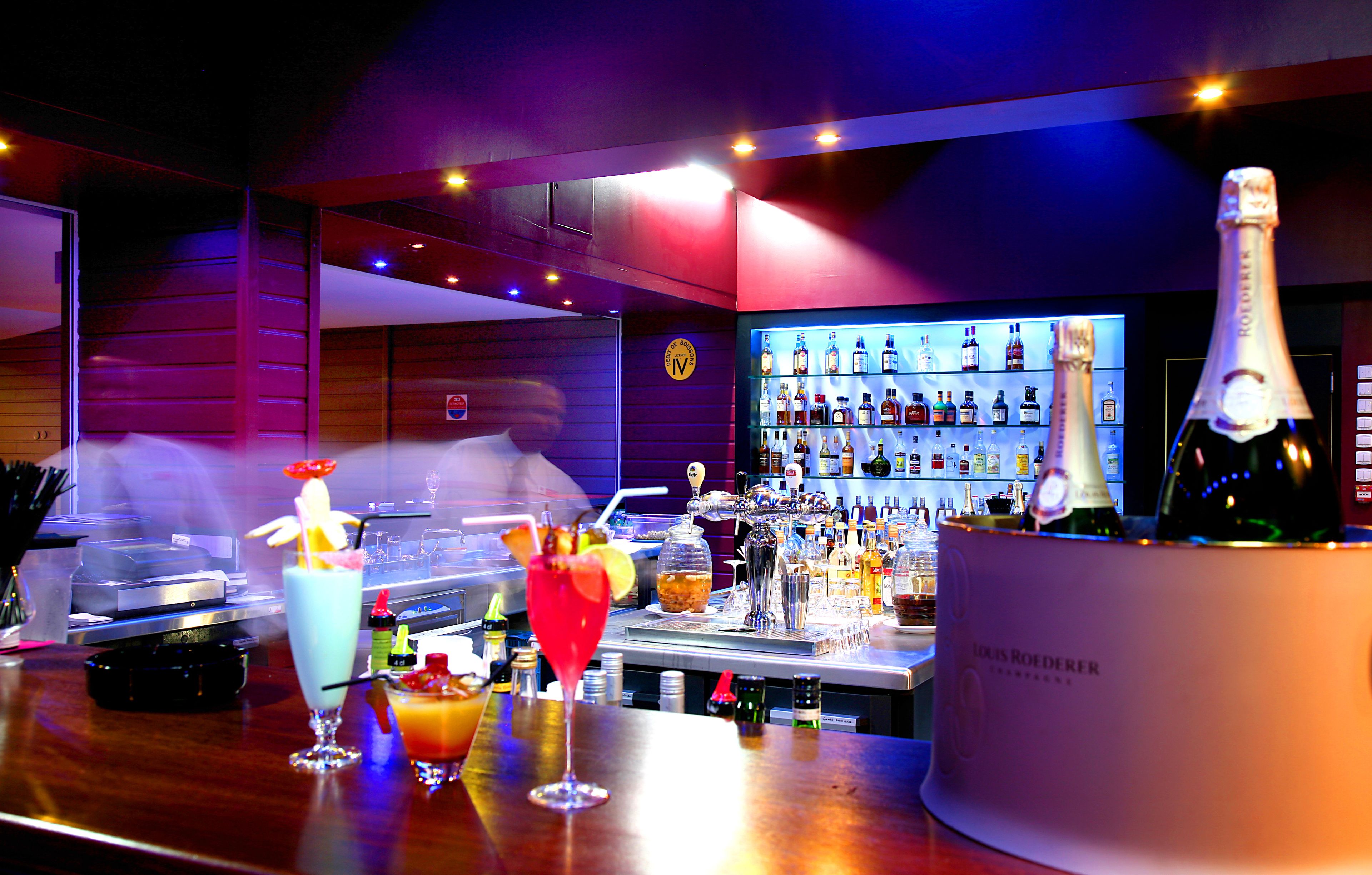Eine Bar mit einer Auswahl an Flaschen und einer großen Champagnerflasche auf der Theke.
