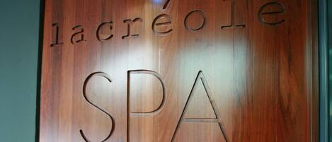 A wooden wall with the words "lacréole SPA" carved into it.
