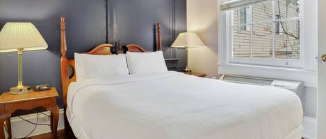 A neatly made bed with white linens, a wooden headboard, and two bedside lamps.