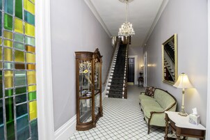 A hallway with a staircase, a green sofa, a lamp, and a mirror on the wall.