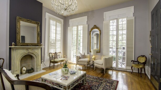 A spacious living room with a fireplace, elegant furniture, and large windows with shutters. - Rathbone Mansions (New Orleans)