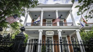 A historic building with a balcony, columns, and flags. - Rathbone Mansions (New Orleans)