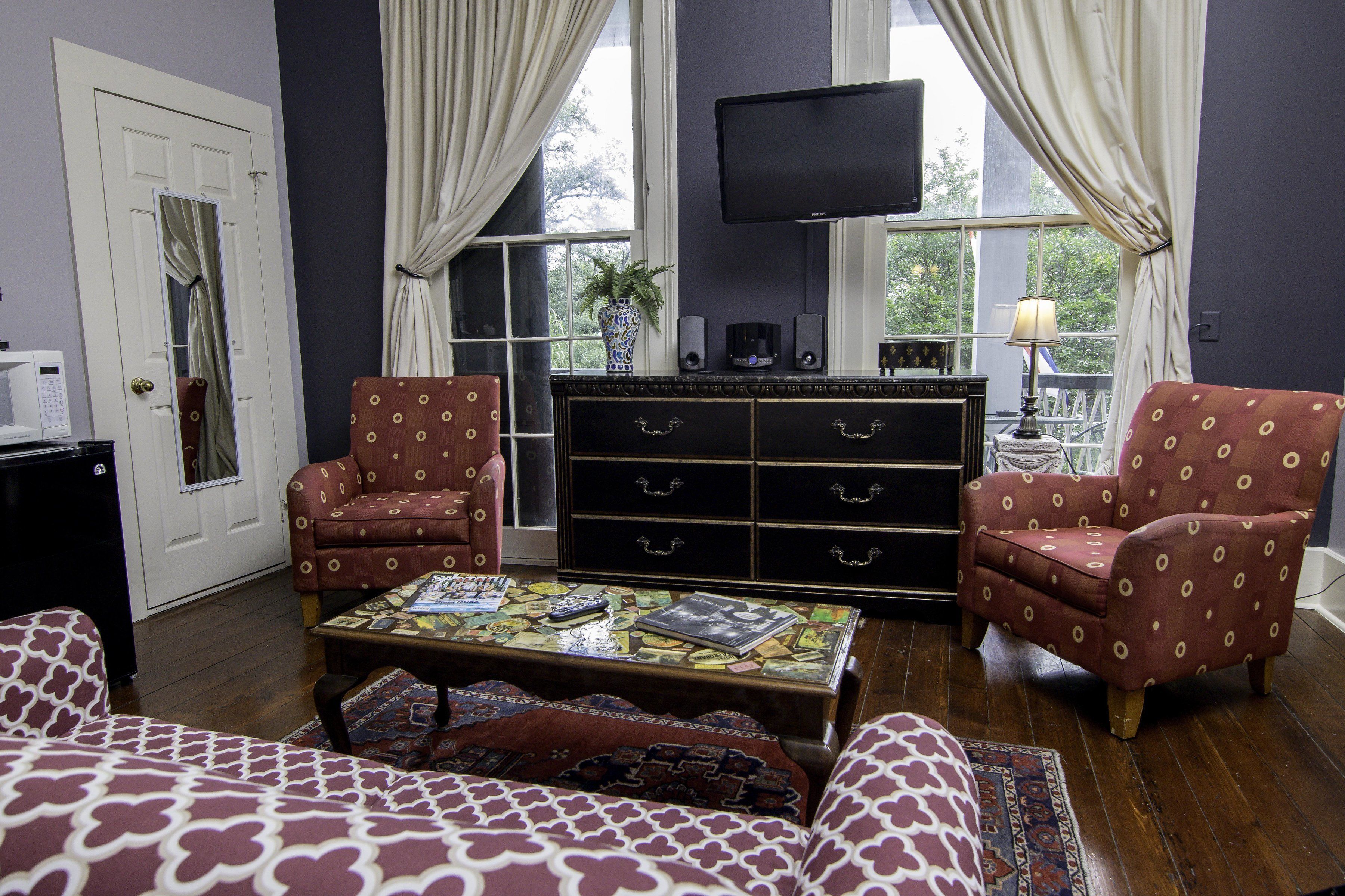 A living room with a sofa, armchairs, a coffee table, a TV, and a cabinet.