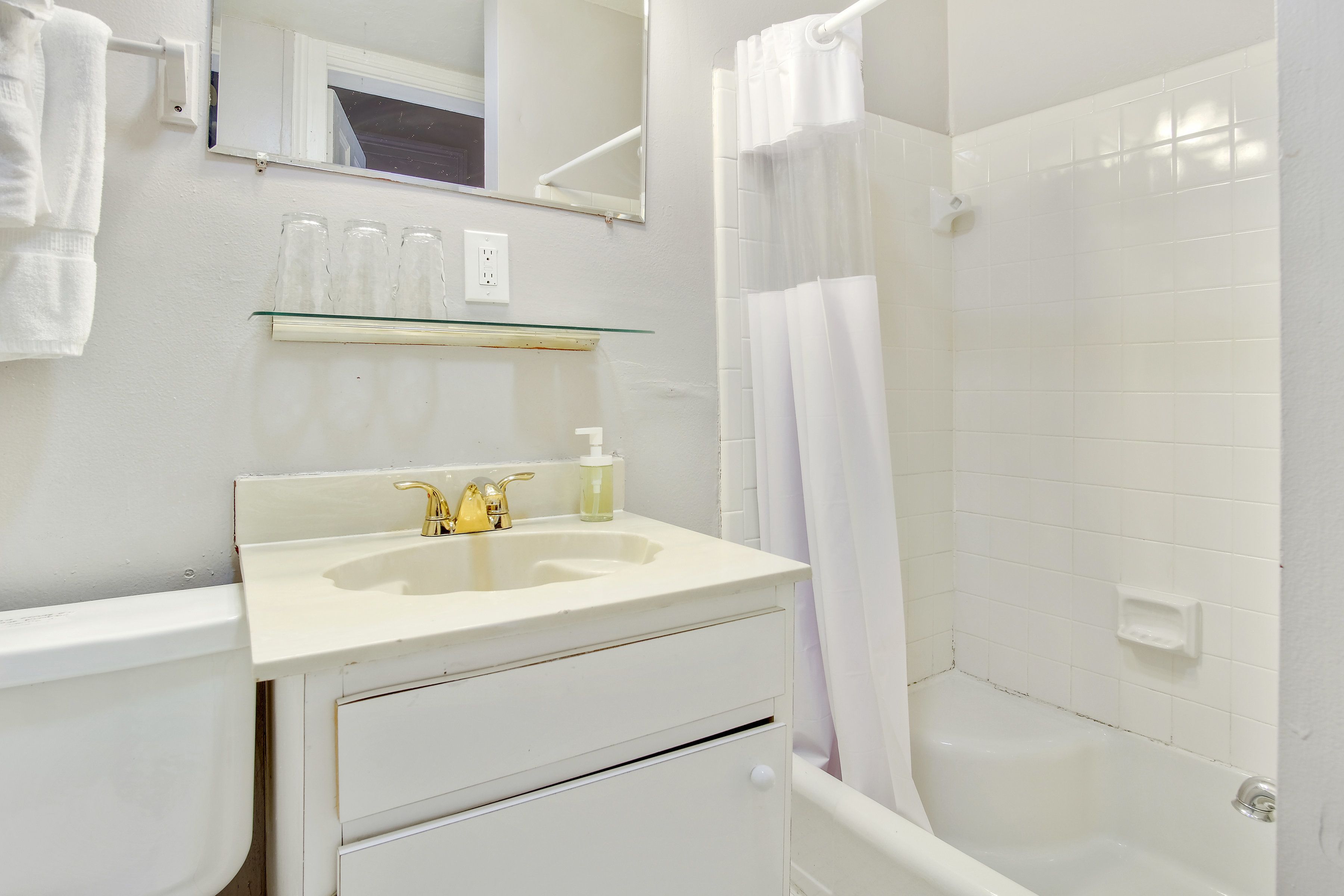 A bathroom with a white sink, mirror, and shower curtain.