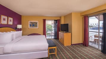 Habitación de hotel con cama, televisión, escritorio y vistas a un cuerpo de agua.