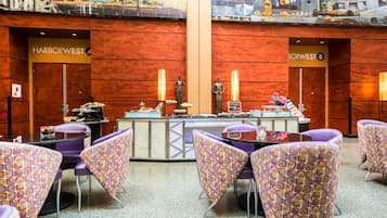 Un área de restaurante con un mostrador, sillas moradas y un mural en la pared.
